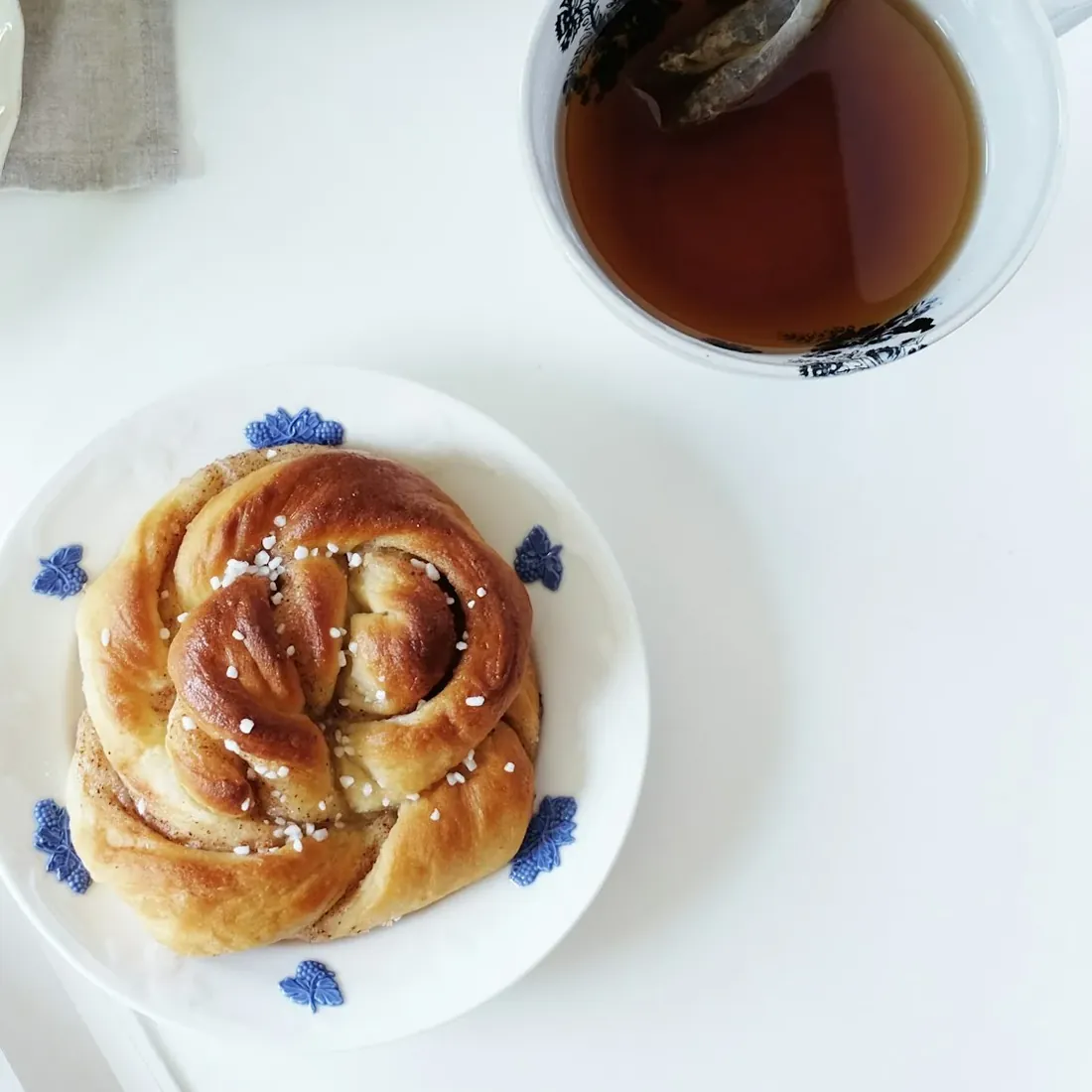 Kanelbulle och en kopp te på ett vitt fikabord