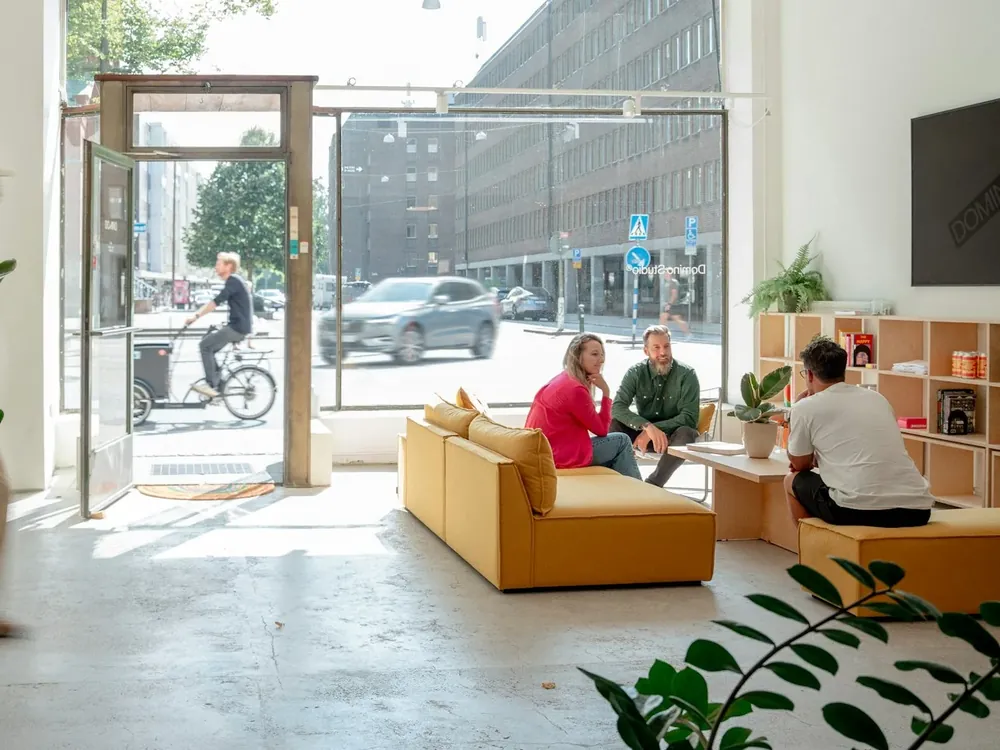 Företagare som pratar i en ljus lounge med gul soffa och stora fönster